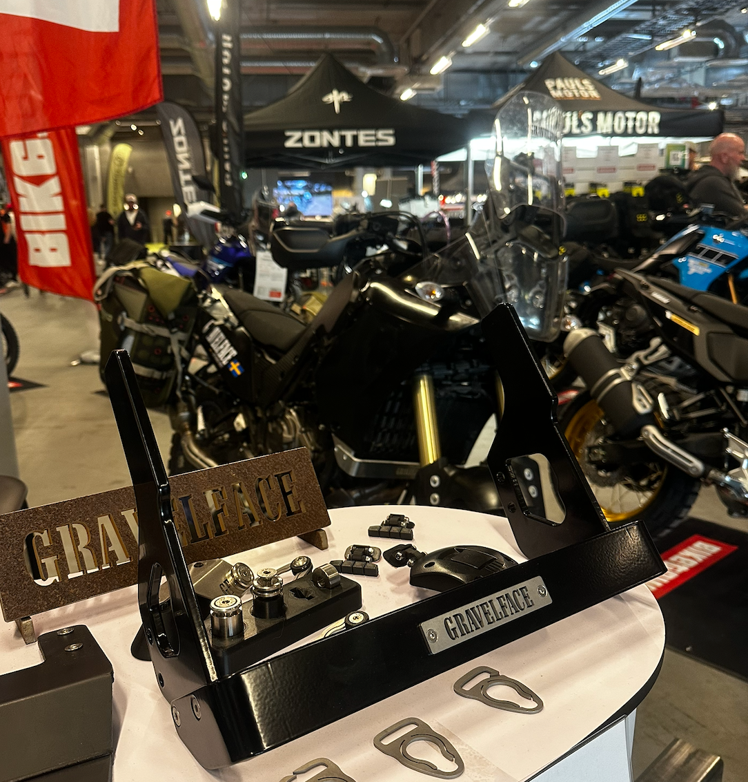 Close-up of a motorcycle part with 'Gravelence' branding at a trade show.